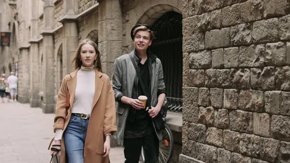 Two Stylish Friend with Cap of Coffee Talking During Walk at the Street alt