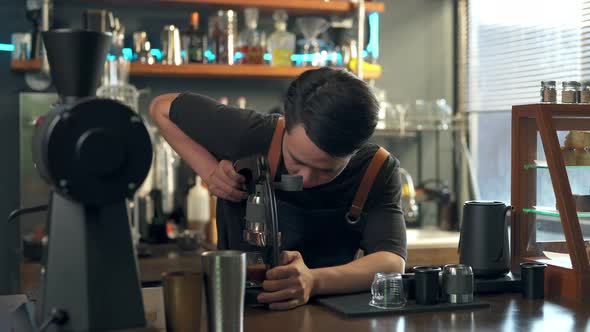 4K Asian man barista making hot espresso shot from flair espresso coffee maker alt
