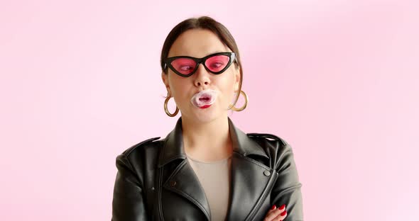 Portrait unusual stylish woman inflates bubble from chewing gum and bursts in pink sunglasses alt