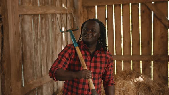 African Farmer Holding Fork Over His Shoulder in the Barn alt