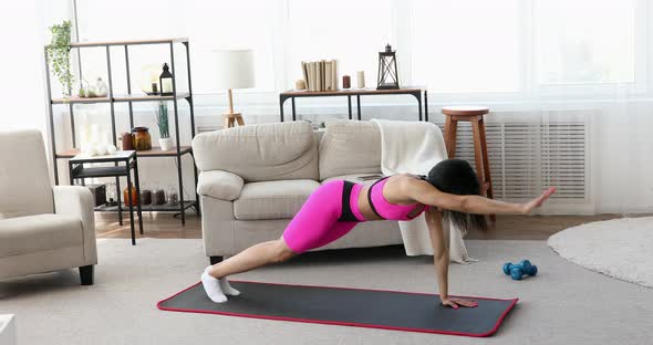 Young black woman making plank flexing legs exercise.