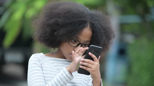 Young Cute African Girl with Afro Hair Using Phone in the Streets Outdoors alt