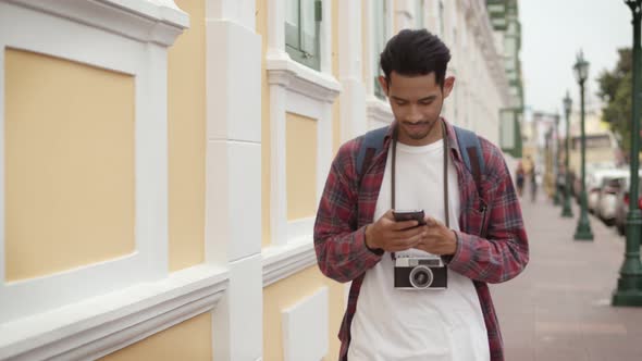 Tourists Asian man using smartphone checking social media while walking on the street.