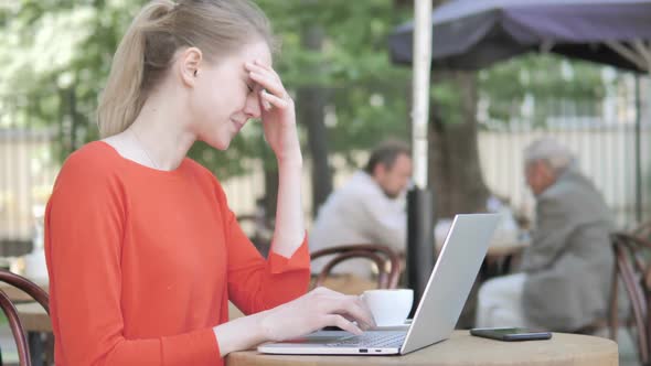 Young Woman with Headache Using Laptop Sitting in Cafe Terrace alt