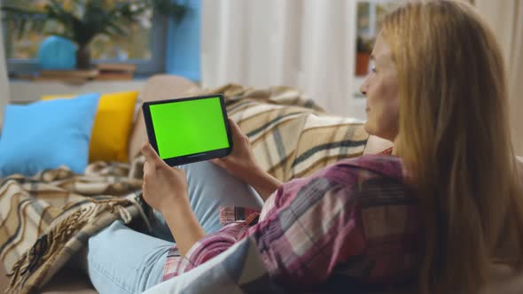 Back View of Happy Mature Woman with Tablet Pc Computer Having Video Call Relaxing on Couch at Home alt