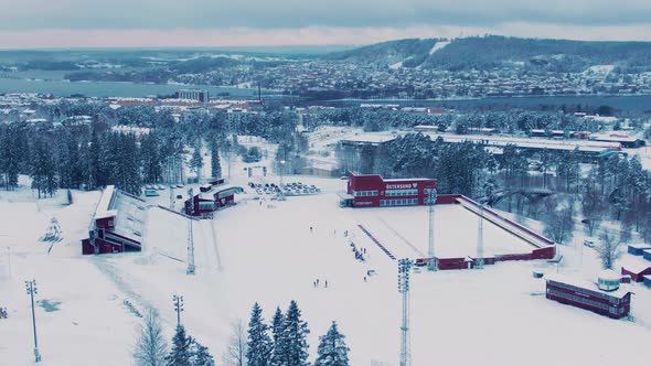 Wide orbiting aerial of Östersund skidstadion and skyline on cold day alt