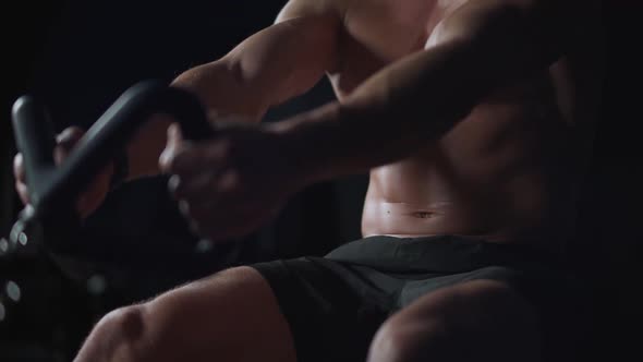 Man Athlete in the Gym Lifting Blocks on Rowing Machine Training on Block Device Night Training alt