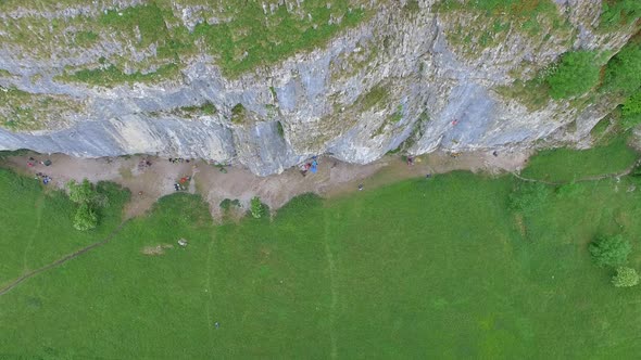 Aerial view of a man rock climbing up a mountain. alt