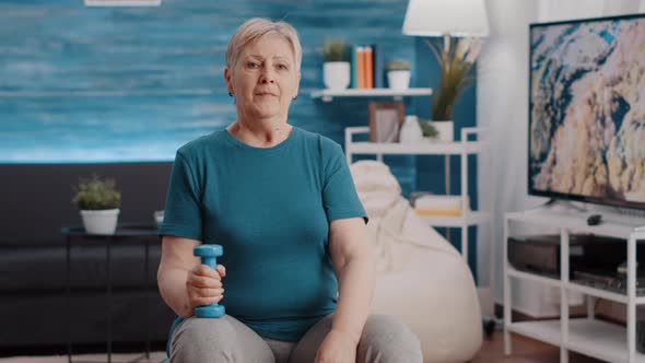 Portrait of Aged Person with Dumbbell in Hand Sitting on Toning Ball alt