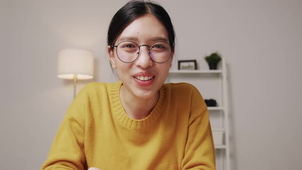 Happy Asian woman smiling face waving hand talking to webcam video call meeting with her friends.