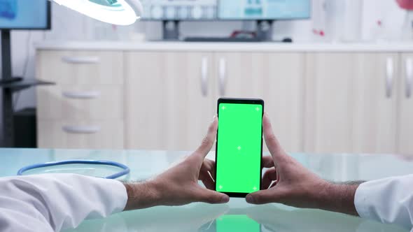 Male Doctor Hands Holding a Phone with Green Screen alt