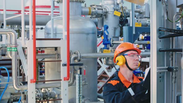 An Engineer Technician in a Helmet Goggles and Headphones Writes Down the Data on the Operation of alt