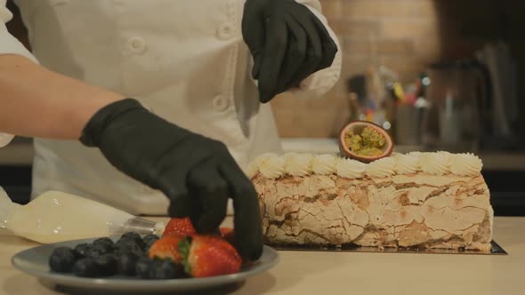 Confectioner Young Woman Decorates Meringue Roll Dessert with Fruits and Berries alt