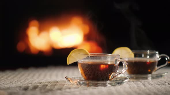 Two Cups of Hot Ow on a Table By the Fireplace, Steam Comes From a Hot Drink alt