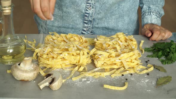 Making tagliatelle pasta. Female hands flours raw fresh pasta on table. Italian Cuisine alt