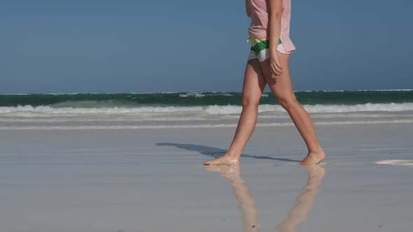 Legs of Young Woman Walking By White Sand Paradise Beach with Tidal Ocean Waves alt
