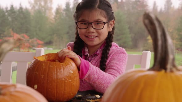 Young girl carving pumpkin for Halloween