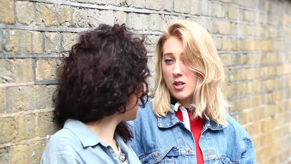 Two women leaning on a wall and talking in London