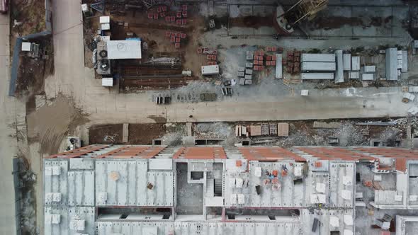 Aerial top-down view of construction cranes and rows of buildings under construction.