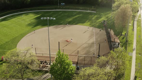 Aerial Drone Shot of Kids Play Baseball Field at Park on Sunny Day alt