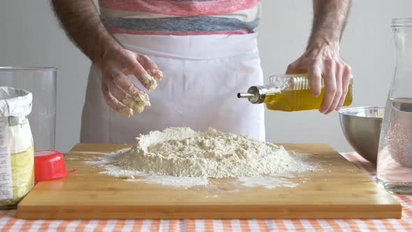 Man pouring oil in flour preparing pizza dough