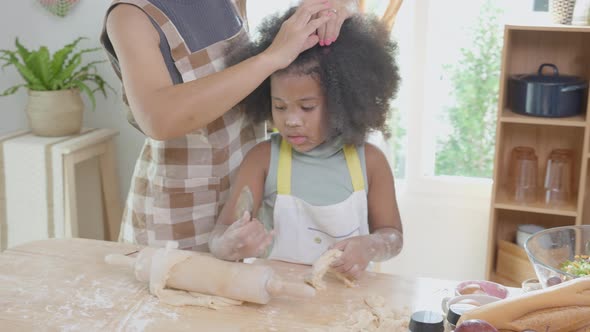 African America family with mother wearing apron rolling thresh flour for cooking with daughter. alt