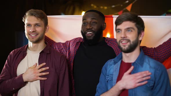 Caucasian and Black Male Friends Singing National Anthem, Waving English Flag alt