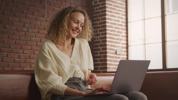 Low Angle Shot of a Caucasian Curly Blond Woman on a Video Call on Her Laptop Computer alt