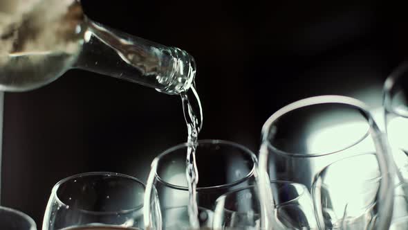 Closeup of a Bottle From Which White Wine is Poured Into a Transparent Glass