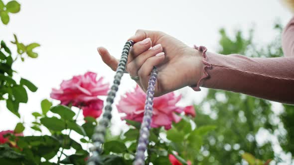 Woman Lit Hand Close Up Counts Rosary - Malas Strands of Gemstones Beads Used for Keeping Count alt