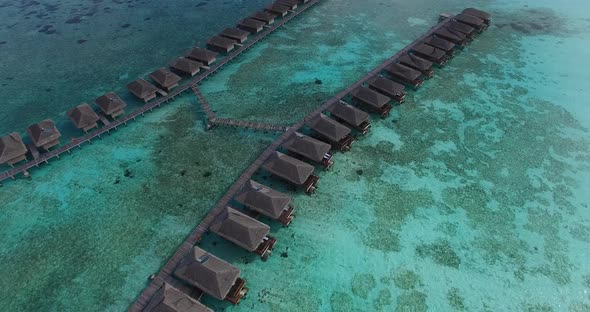 Aerial view of over water villas on Maldivian island with turquoise crystal clear water