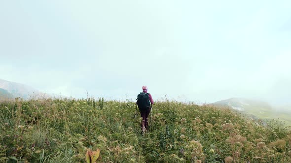 Young Woman with Backpack Walks Towards the Summit. Slow Motion. Lady Is Hiking in Beautiful alt