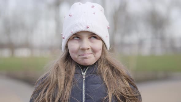 Close-up Face of Funny Little Girl Making Faces. Portrait of Brunette Caucasian Kid Grimacing on alt