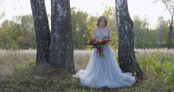 A Young Woman Dressed in a Gray Wedding Dress Celebrates Her Wedding. She Has Flowers in Her Hand alt