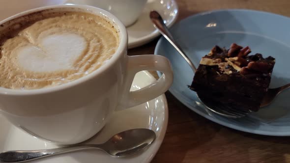 Cup of coffee and chocolate cake close-up in a cozy cafe.