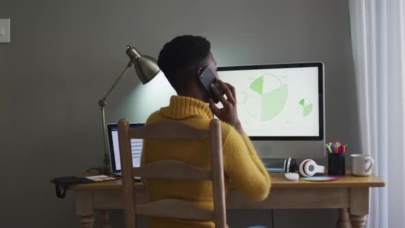 African american woman talking on smartphone while working from home alt