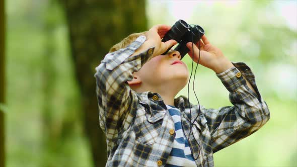 Young Boy Looking Through Binoculars In Wood