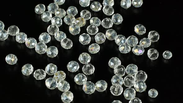 White beads for making jewelry on a black surface and rotating. alt