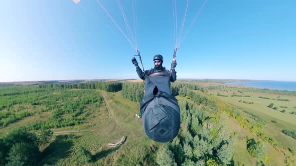 A Person Is Flying the Paraplane Over the Forest in a Front View alt