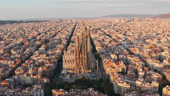 Rising pan down drone shot of La Sagrada Familia Basilica Barcelona at sunrise alt