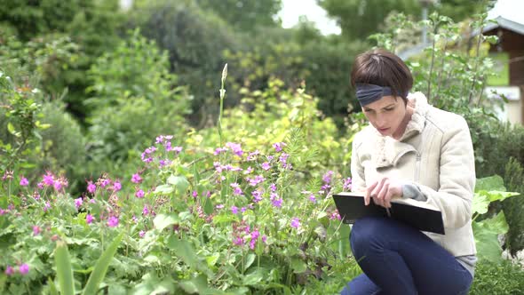 Woman examining flowers in garden