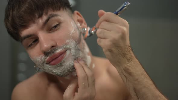 Closeup Front View Man Shaving Cheek Smiling in Slow Motion alt