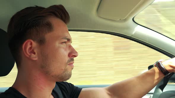 Young Handsome Man Drives a Car on the Road in the Town alt