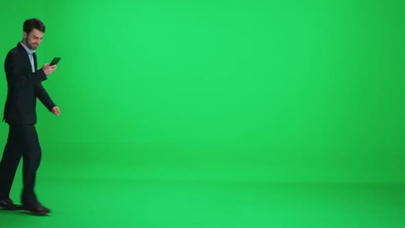 Passerby Young Man in a Suit Walks on a Green Background and Uses a Smartphone Template on a alt