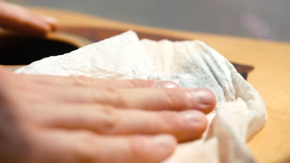Musician cleaning and oiling an acoustic guitar neck and body. alt