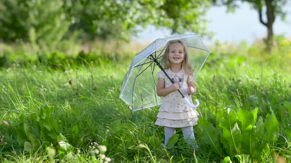 Cute little girl in a dress posing Outdoors in a green park. alt