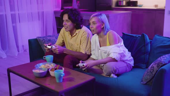 Excited Funny Young Adult Couple Gamers Holding Controllers Playing Video Game alt