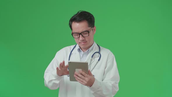 The Front View Of Asian Doctor With Stethoscope Using Tablet While Walking On Green Screen alt