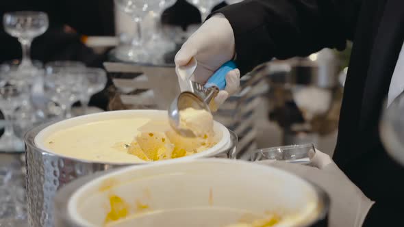 Closeup of Waiter's Hands in White Gloves with Ball of Ice Cream