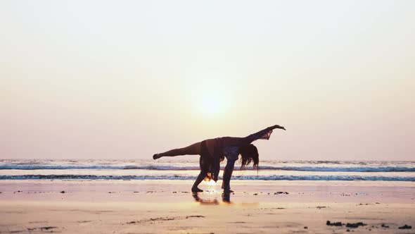 Silhouette of Young Gymnast Woman Doing Handspring on Sandy Beach